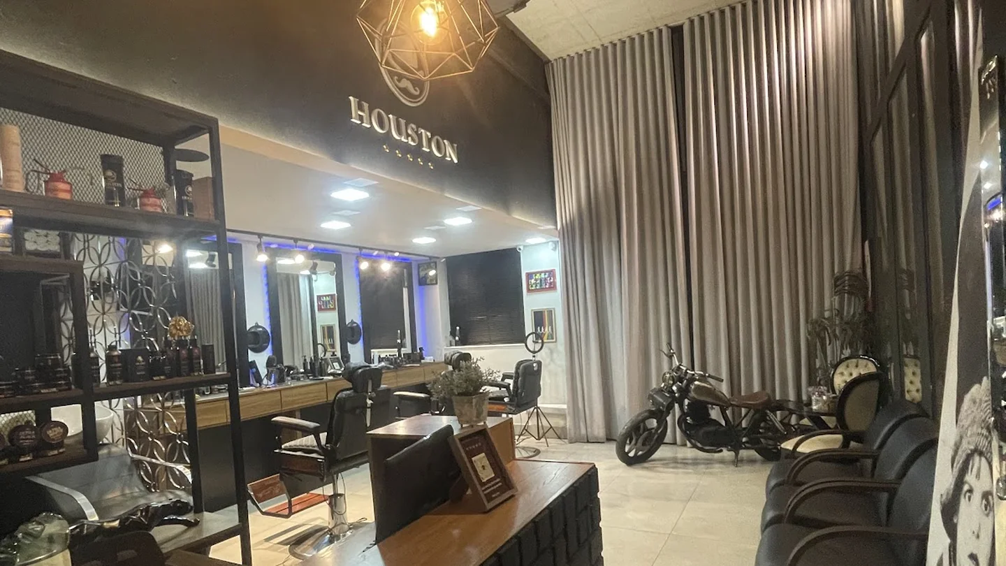 Interior da Houston no Jardim da Cidade, com espelhos, cadeiras e o logo da barbearia.
